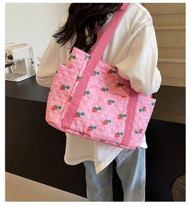 Detail view of pink quilted tote bag with cute strawberry pattern and wide fabric strap