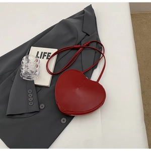 Dettaglio della borsa a tracolla rossa a forma di cuore con pelle liscia e cerniera laterale