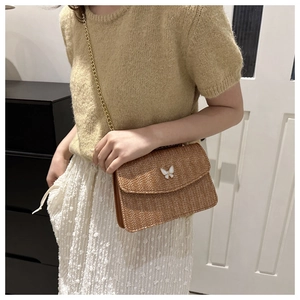 Brown woven straw crossbody bag with white butterfly clasp and gold chain detail