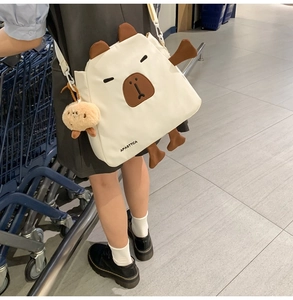 Vue détaillée d'un sac bandoulière blanc en nylon motif capybara avec son charme peluche