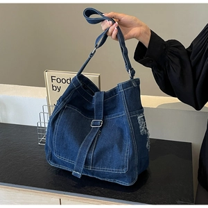Detail of dark blue denim tote with contrast white stitching and frayed fringe edges