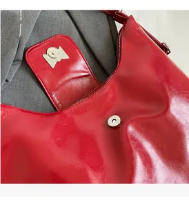 Detail of red patent leather handbag showing silver magnetic closure and fine stitching