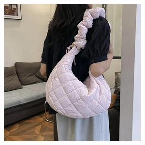 Detail of pink quilted hobo bag with pleated shoulder strap worn by a female model