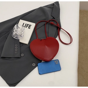 Dettaglio della borsa a tracolla rossa a forma di cuore con doppia cerniera e smartphone