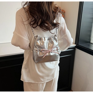 Détail du sac seau métallisé argenté avec nœud rose et chaîne porté par un mannequin