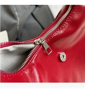 Close-up of red patent leather bag with silver metal zipper and herringbone lining