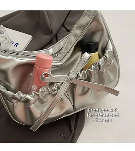 Detail of silver metallic PU leather hobo bag showing front pocket and bow decoration
