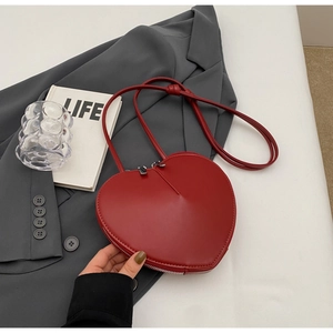 Dettaglio di una borsa a tracolla rossa a forma di cuore con cerniera e cinturino a nodo