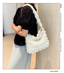 Detail of creamy white puffy cloud bag with chunky woven texture and broad shoulder strap