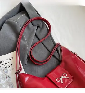 Detail of red PU leather shoulder bag with a shiny finish and silver metal bow buckle