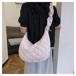 Detail view of pink quilted nylon hobo bag with padded shoulder strap on female model