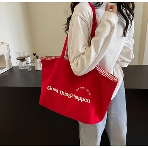 Detail of red canvas tote bag with Good Things Happen text and striped lining