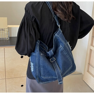 Detailansicht der dunkelblauen Denim-Umhängetasche mit weißen Nähten und Fransenstruktur