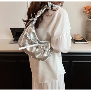 Detail of silver metallic crescent bag with bow decoration and ruched shoulder strap