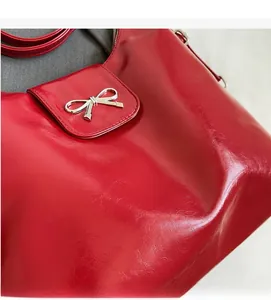 Detailed close-up of dark red oil wax PU leather texture and silver metal bow ornament