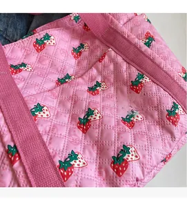 Close-up of pink quilted tote bag with red strawberry patterns and soft texture detail