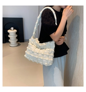 Detail of the white quilted shoulder bag showing the textured puffy woven fabric pattern