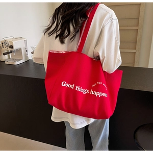 Detail of red canvas tote bag featuring white text print and striped lining detail