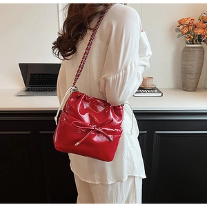 Détail du sac seau rouge brillant en PU avec nœud et bandoulière en chaîne argentée