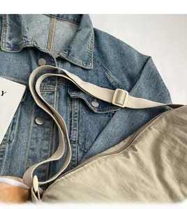 Detail of adjustable long shoulder strap and smooth zipper on beige fabric crossbody bag