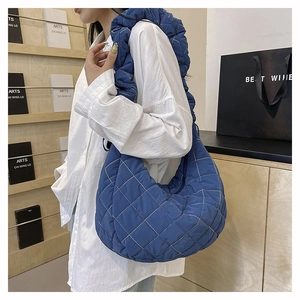 Detail of navy blue quilted nylon hobo bag showing padded texture and wide shoulder strap