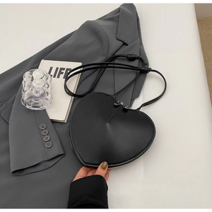 Dettaglio della borsa a tracolla nera a forma di cuore con pelle liscia e cerniera argento