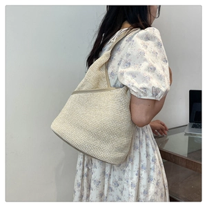Lifestyle shot of a cream knitted tote bag styled with a blue floral dress for summer