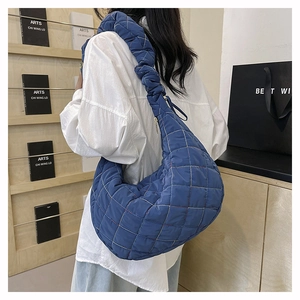 Detail of blue quilted hobo bag with ruched shoulder strap and colorful stitching