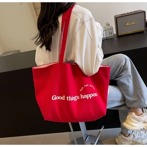 Detail of red canvas tote bag with Good things happen text and red striped lining