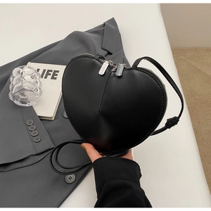 Dettaglio di una borsa a tracolla nera a forma di cuore in pelle opaca con doppie zip
