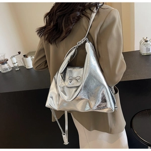 Silver metallic PU shoulder bag featuring a decorative metal bow and chain strap detail