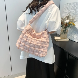 Pink quilted woven shoulder bag with golden metallic buckle and wide strap on model