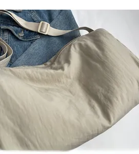 Detailed macro view of soft beige fabric texture and adjustable strap on cross-body bag