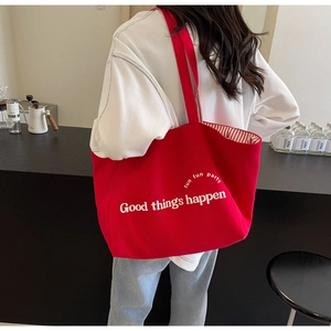 Detail of red canvas tote bag with Good Things Happen print and red striped lining fabric