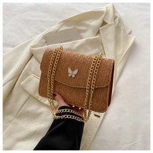 Brown woven crossbody bag with white butterfly accessory and gold metal chain strap