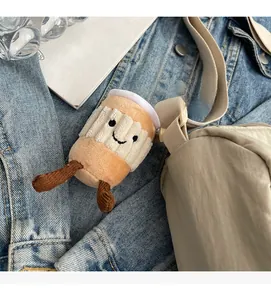 Close-up of a plush cup-shaped bag pendant with a smiling face on a crossbody strap