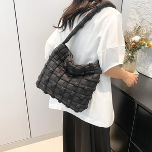 Detail view of a black woven puffy tote bag with soft padded texture and shoulder strap
