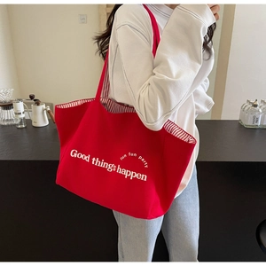 Macro detail of red canvas tote bag with white text and striped lining in a cafe