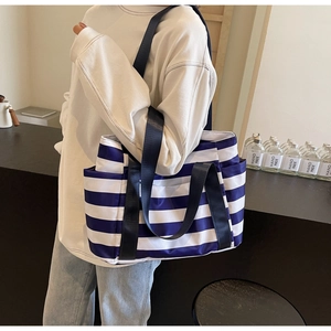 Detail view of a striped blue and white fabric tote bag with side pockets and long straps