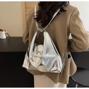Detail of silver metallic handbag with bow accent and pleated design on model
