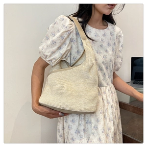 Close-up of a woven knit hobo bag with beige leather trim and straw texture detail