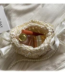 Detailed view of white woven bag with silk ribbon bow and pearls showing interior capacity