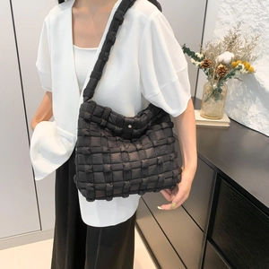 Close-up of black quilted puffer tote bag with thick woven texture and metal snap closure
