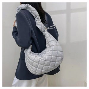Detail view of a quilted nylon crossbody bag with ruffled strap on a model shoulder