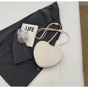 Dettaglio della borsa a cuore bianca in pelle PU su un blazer grigio raffinato