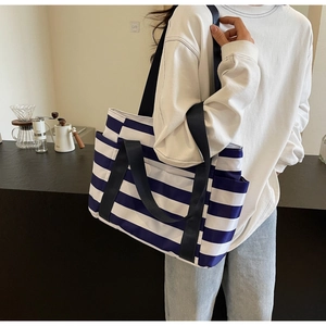 Close-up of blue and white striped tote bag with wide strap handles and side pockets
