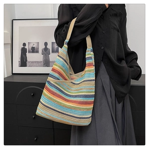 Detail of colorful striped knitted tote bag with brown leather strap worn by a model