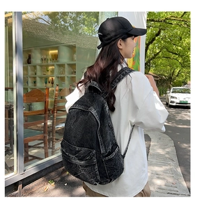 Outdoor shot of a black acid-washed denim backpack for women with adjustable straps