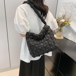 Fashionable black quilted puffer shoulder bag shown on model in a minimalist setting