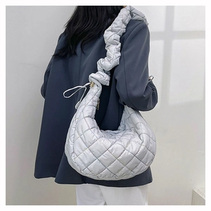 Macro view showing the silver-grey quilted puffer hobo bag with pleated shoulder strap detail
